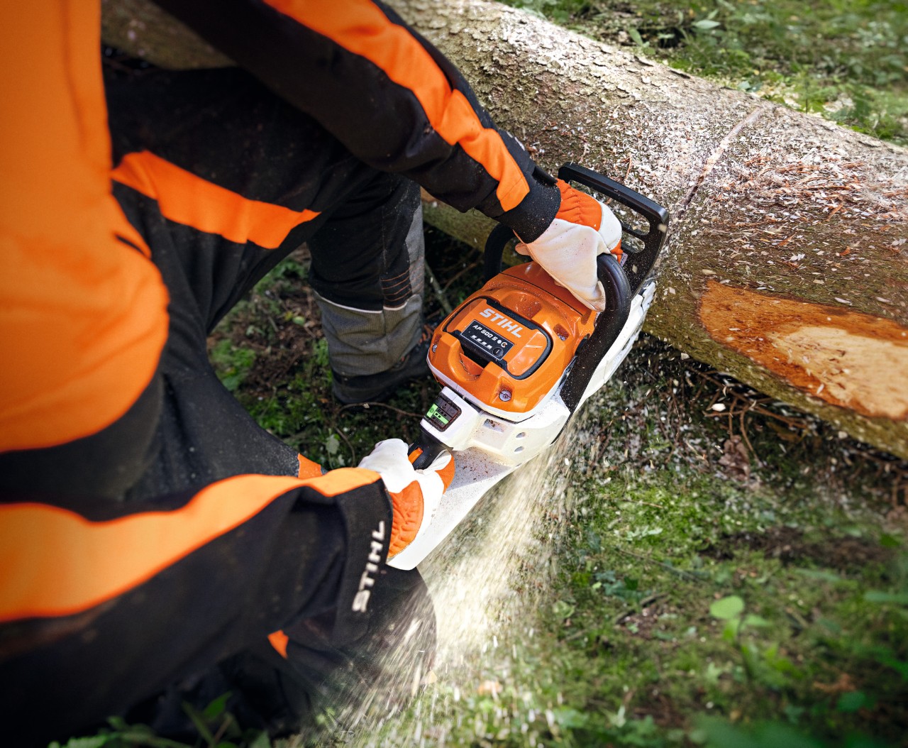 Lähikuva henkilöstä, joka sahaa puunrunkoa akkukäyttöisellä STIHL MSA 300 -moottorisahalla