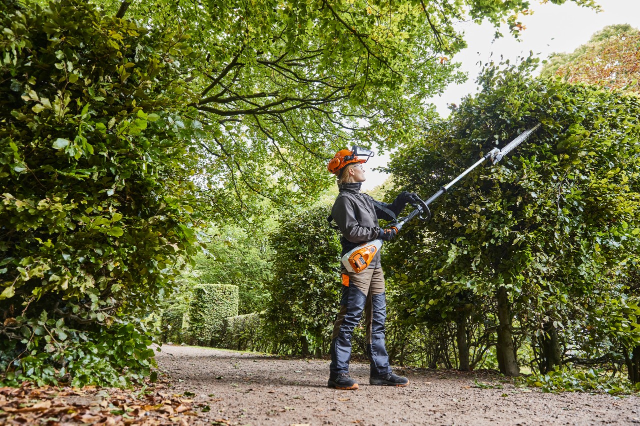 Puutarhuri ja maisemoija leikkaamassa pensasaitaa akkukäyttöisellä STIHL HLA 135 -pensasleikkurilla.