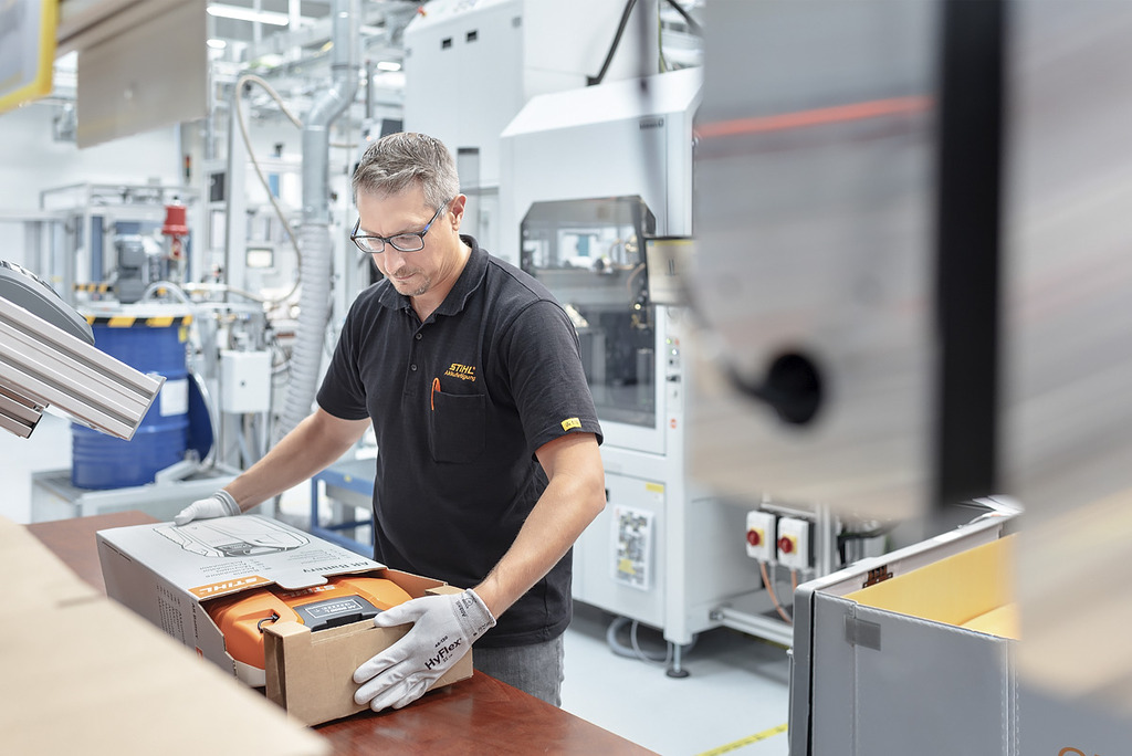En anställd inom batteriproduktionen packar ett STIHL-batteridrivet verktyg i en låda.