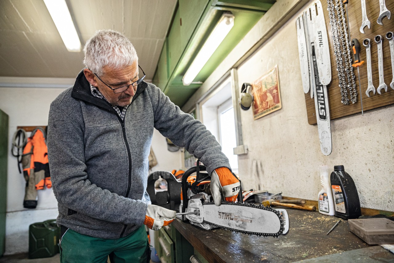 Mies korjaamossa ruuvaamassa STIHL Rollomatic E -terälevyä moottorisahaan 