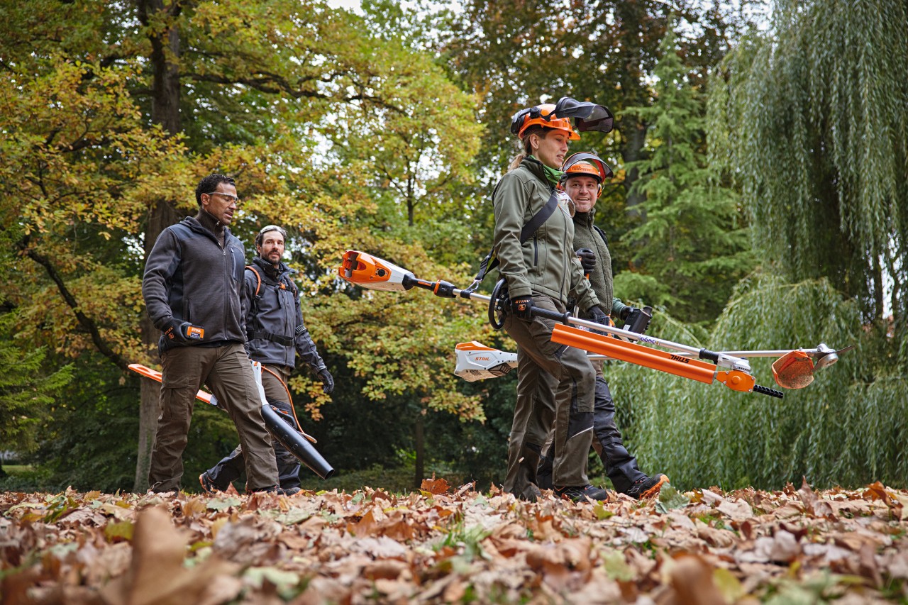 Neljä STIHL-ammattilaista kävelemässä polulla akkutyökalujen kanssa