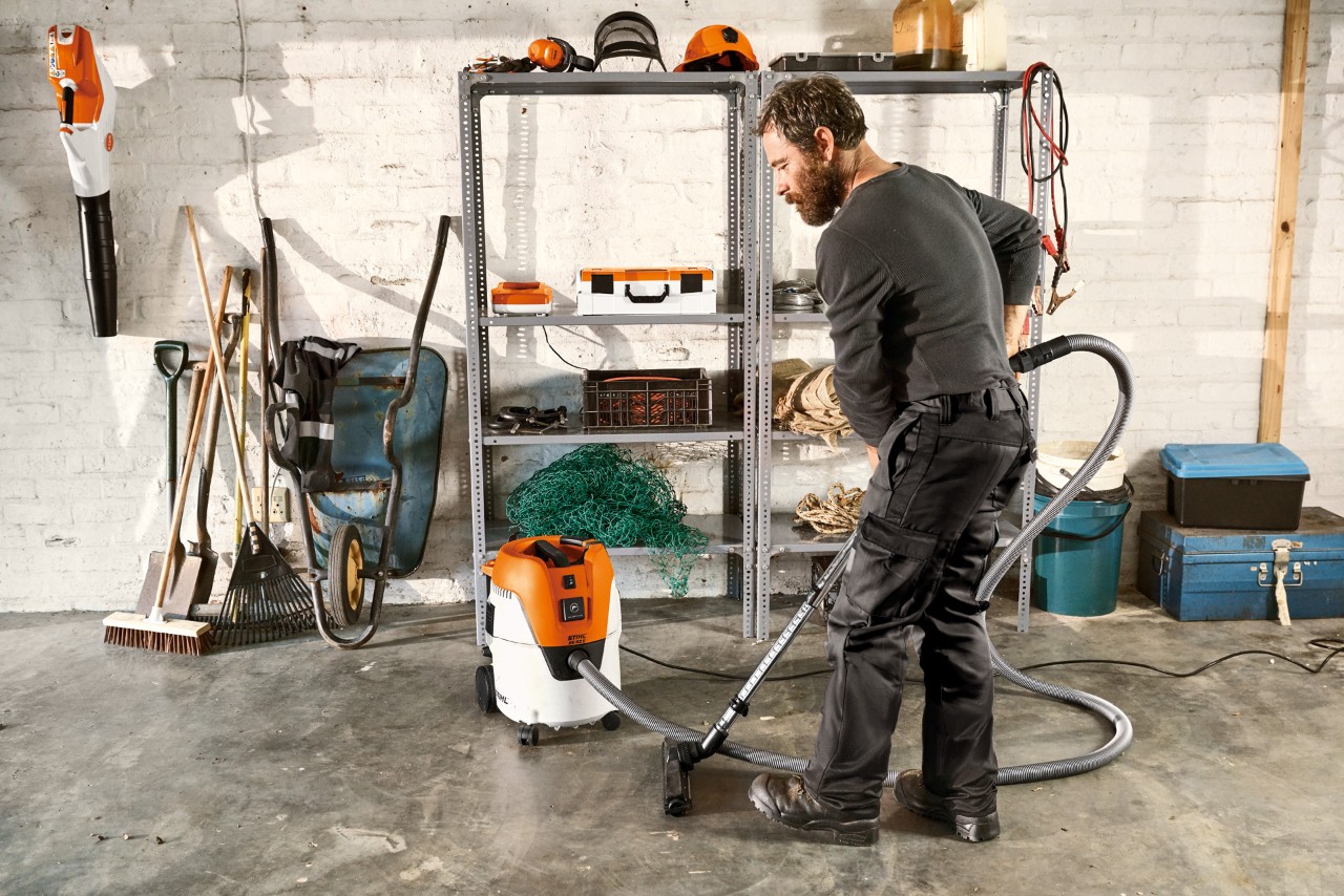 Mies imuroimassa autotallin lattiaa STIHL SE 62 E -märkä-kuivaimurilla