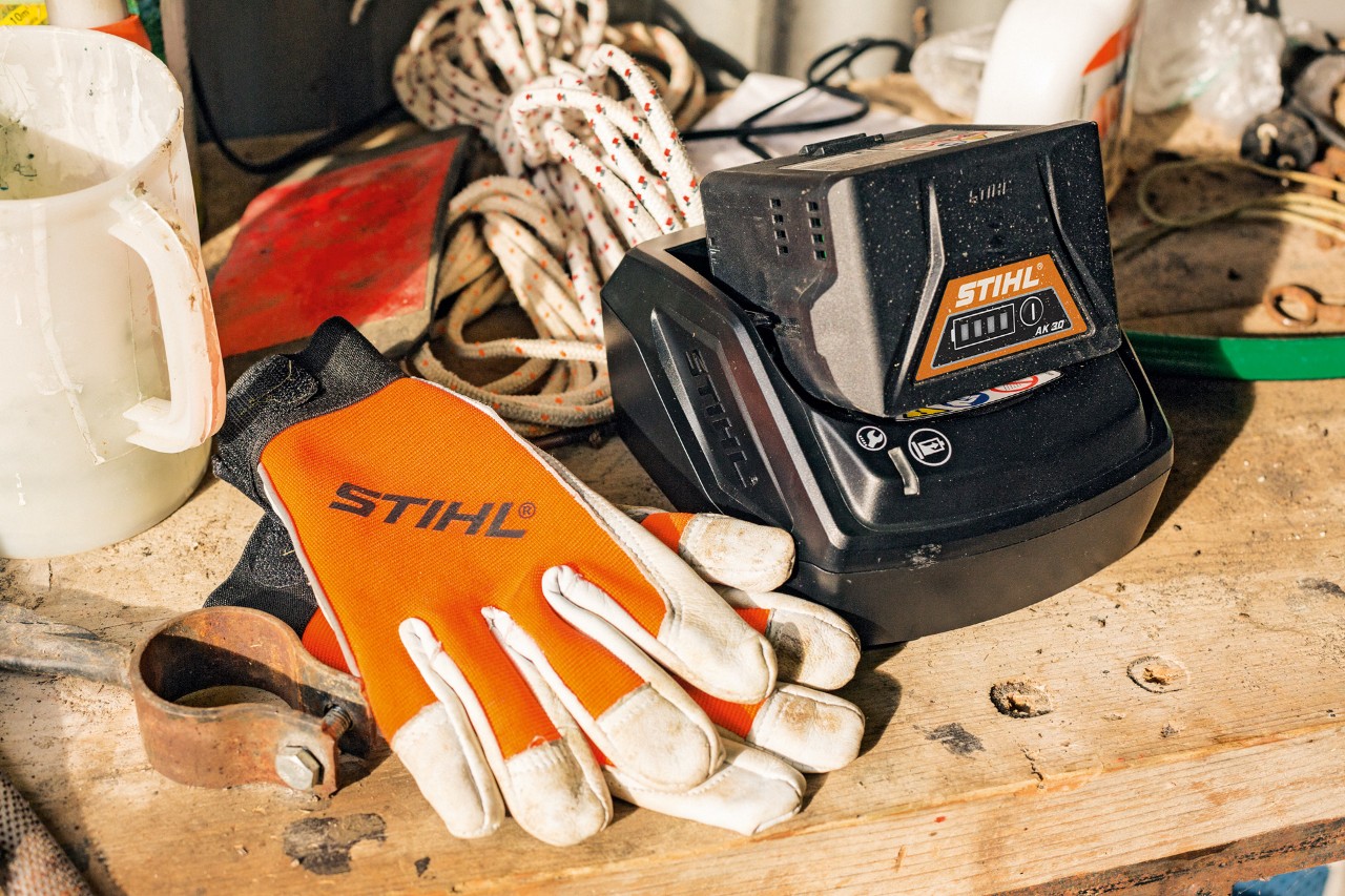 AK-sarjan litiumioniakut latautumassa STIHL-käsineiden ja -työkalujen vieressä