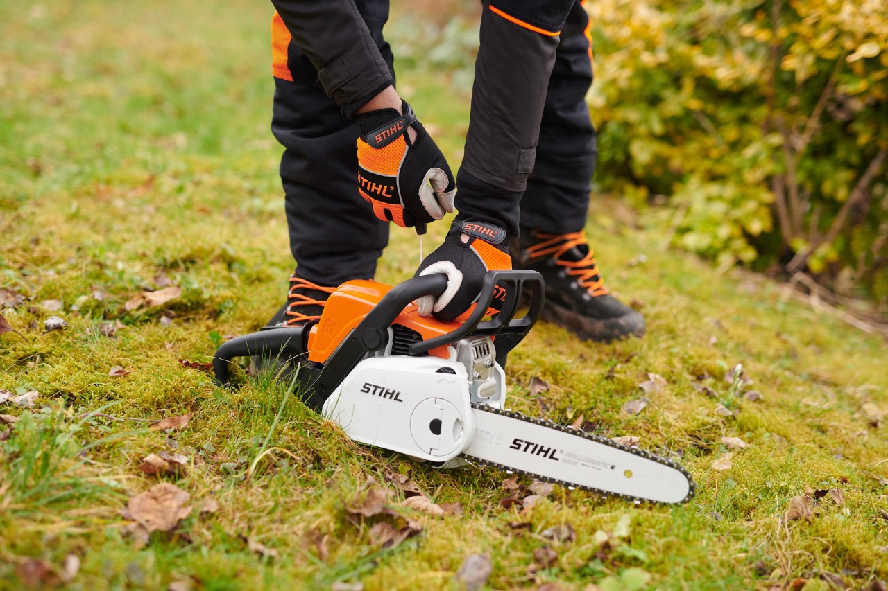 Bensiinikäyttöisen STIHL MS 180 C-BE -moottorisahan käynnistäminen maassa