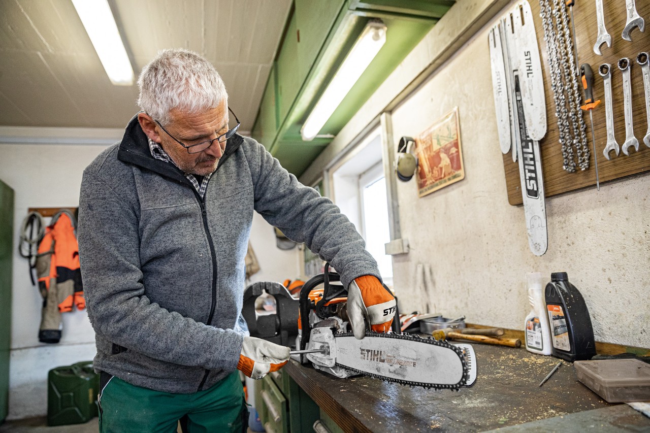 Mies kiristämässä STIHL-moottorisahan ketjua korjaamolla