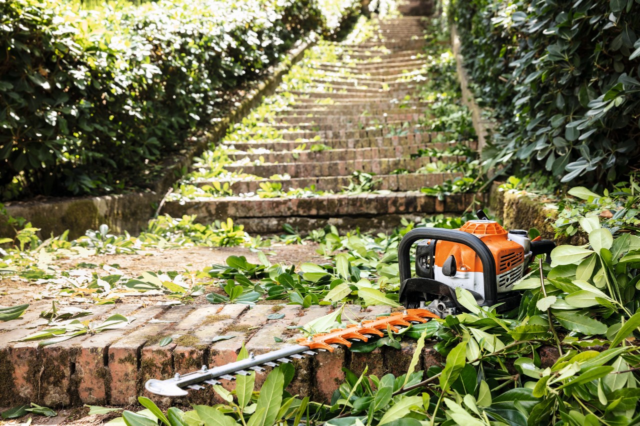 Bensiinikäyttöinen STIHL HS 82 T ‑pensasleikkuri portailla ennen huoltoa