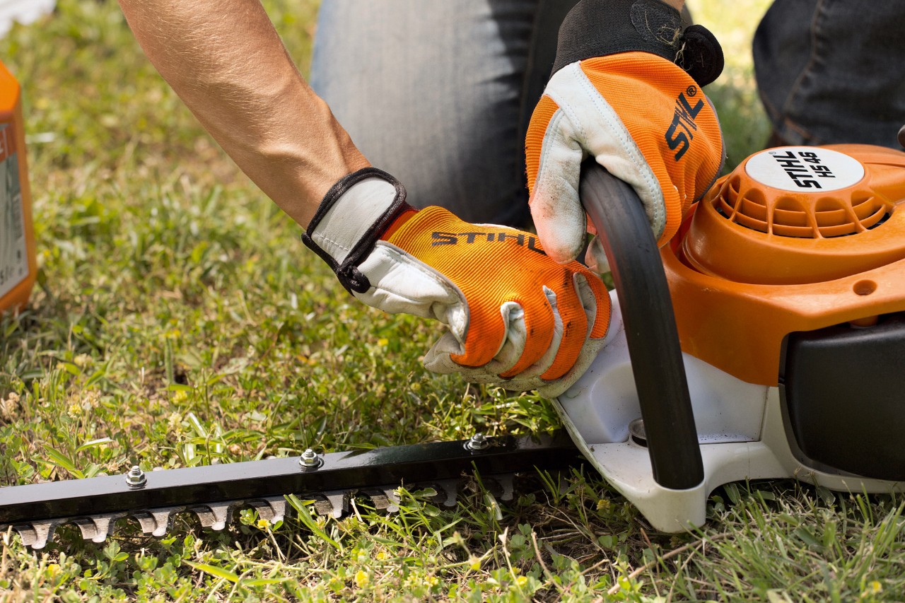 Lähikuva bensiinikäyttöisestä STIHL HS 46 -pensasleikkurista, jota pyyhitään liinalla
