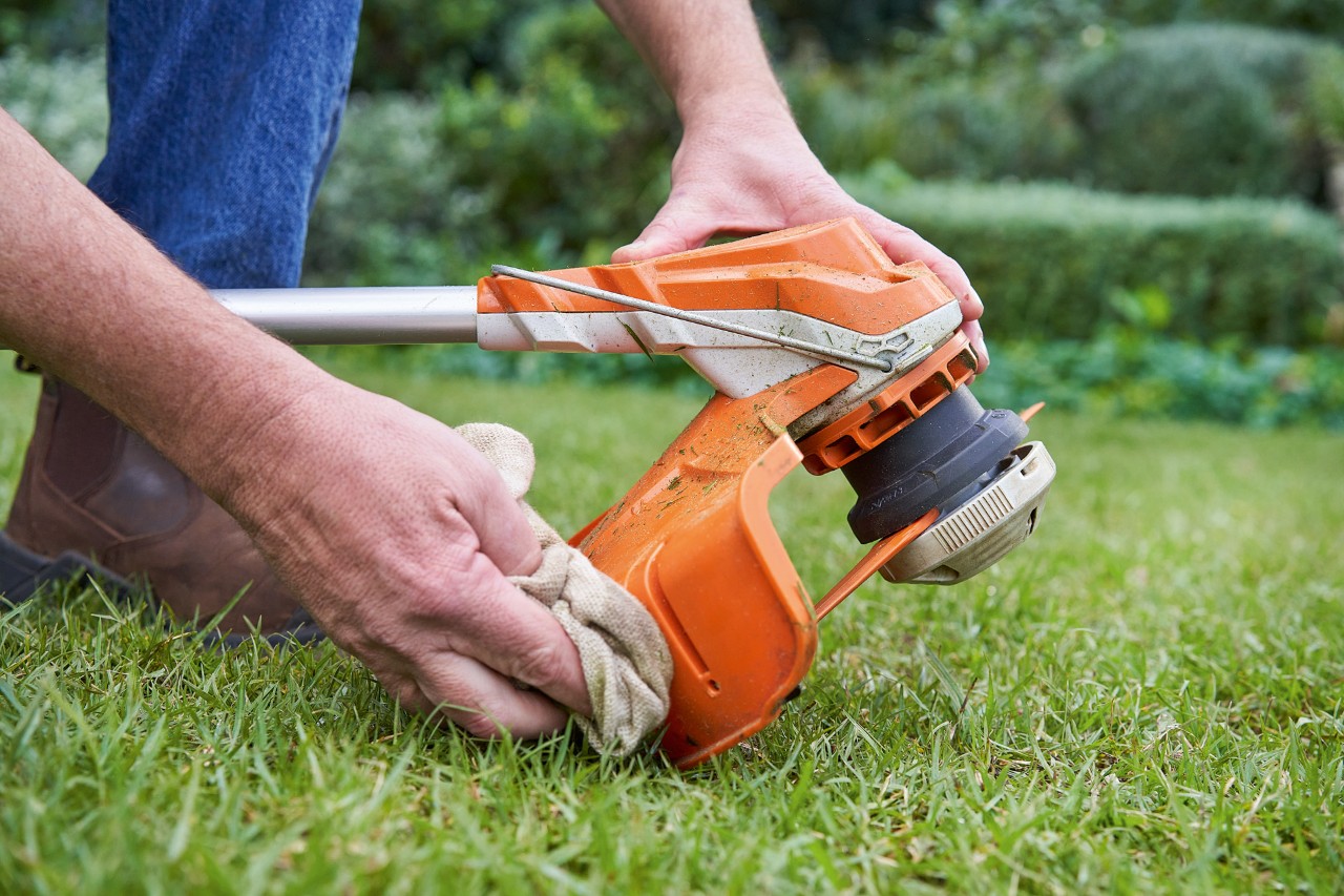 Henkilö puhdistamassa STIHL-raivaussahan suojusta kostealla liinalla