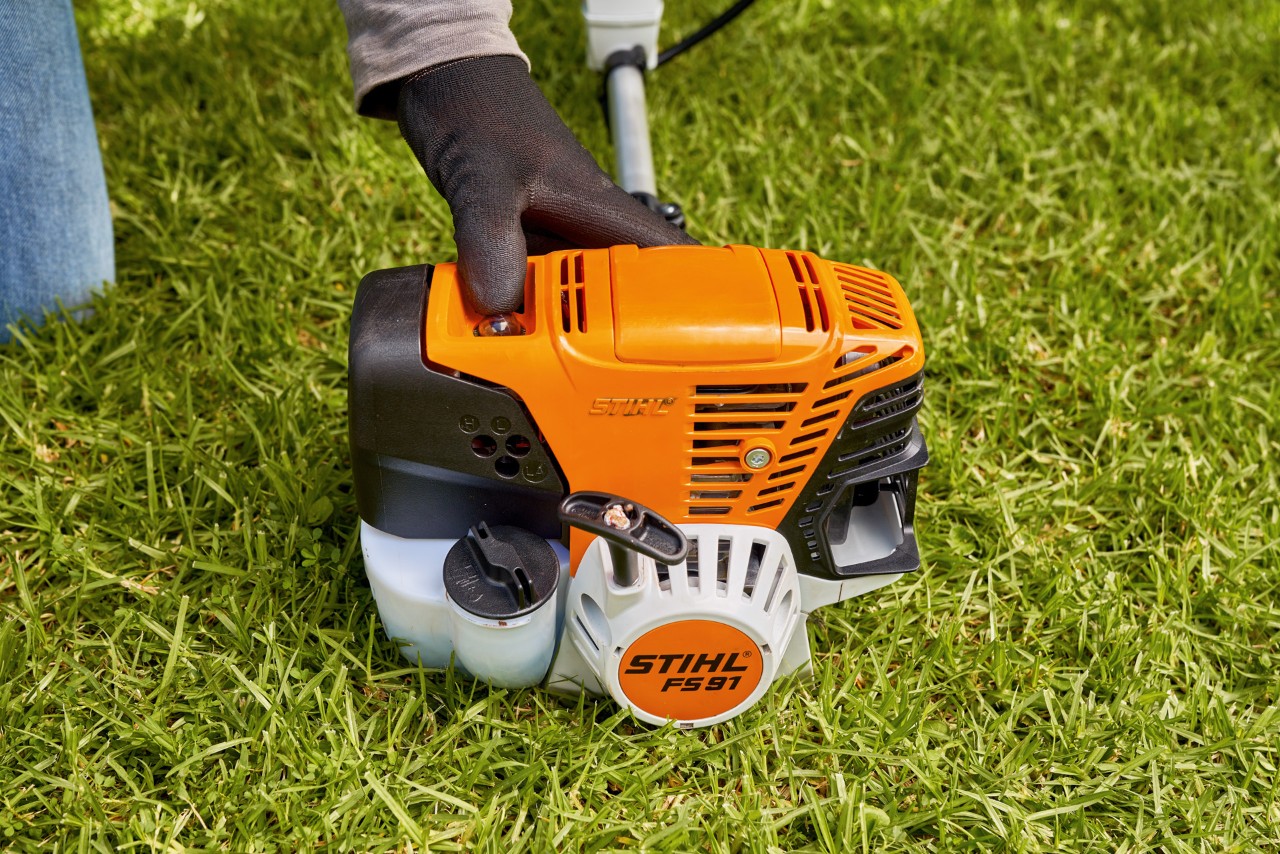 Mies käynnistämässä bensiinikäyttöistä STIHL FS 91 -raivaussahaa painamalla polttoainepumppua