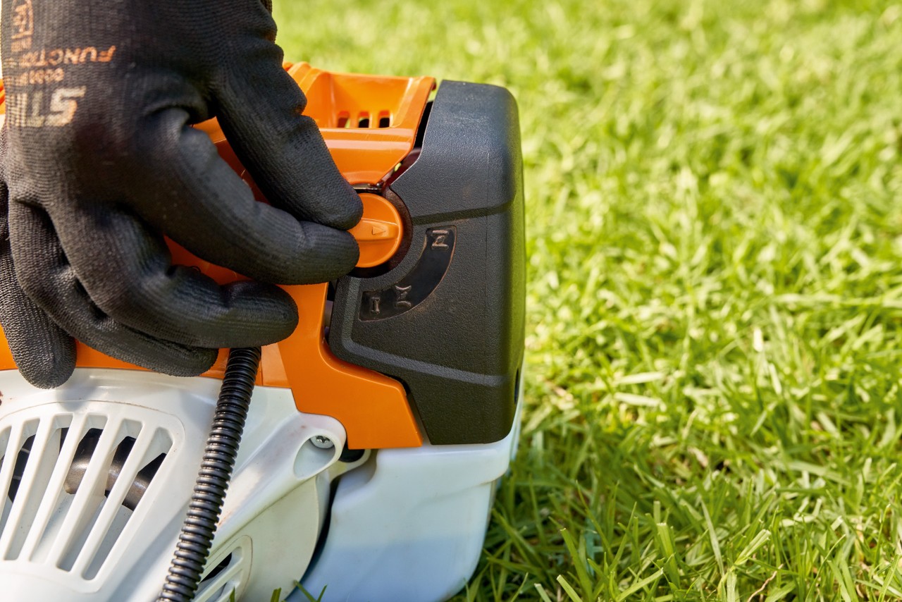 Mies säätämässä bensiinikäyttöisen STIHL FS 91 -raivaussahan polttoainepumpun vipua sen käynnistämiseksi