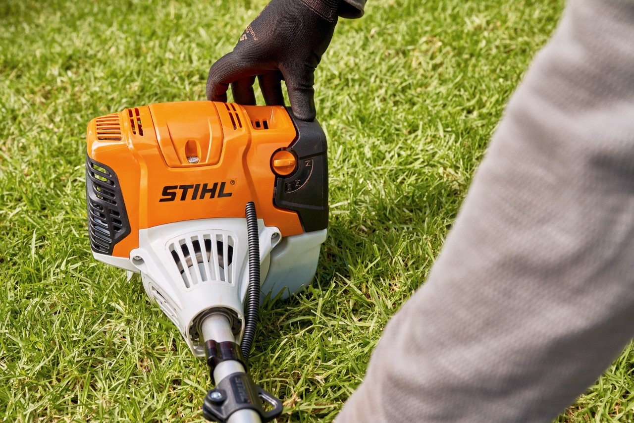 Mies painamassa bensiinikäyttöistä STIHL FS 91 -raivaussahaa lujasti maahan