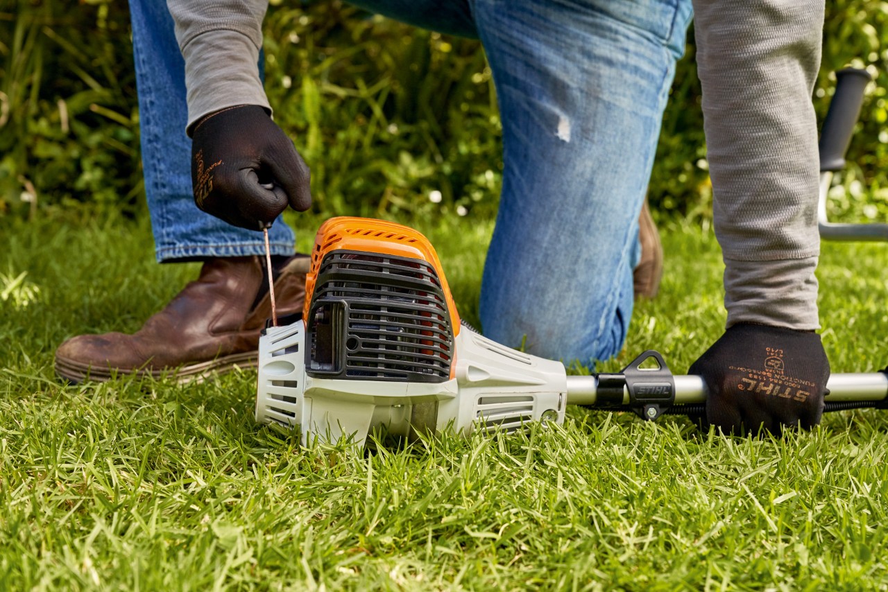 Mies vetämässä bensiinikäyttöisen STIHL FS 91 -moottorisahan käynnistysnarua 