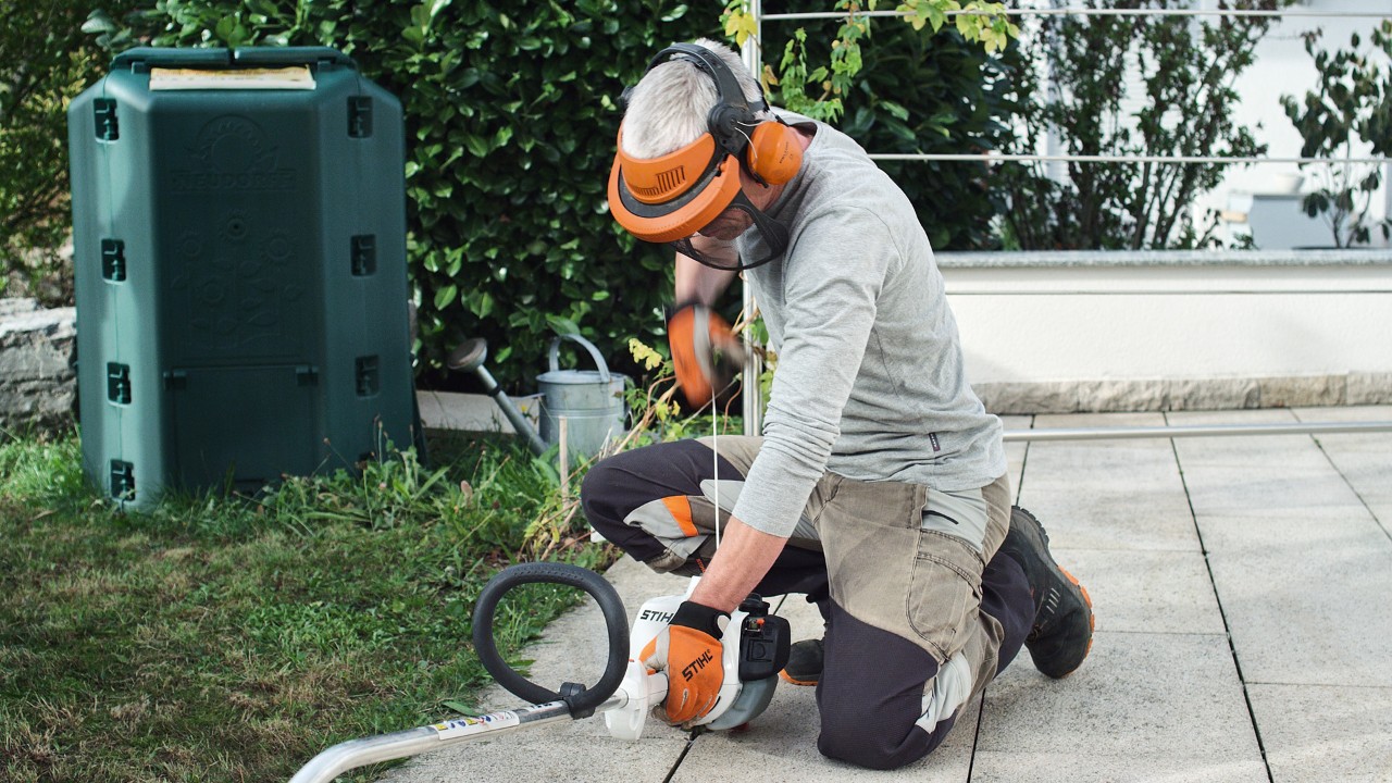 Suojavaatteita käyttävä henkilö vetämässä bensiinikäyttöisen STIHL FS 38 -raivaussahan käynnistysnarusta