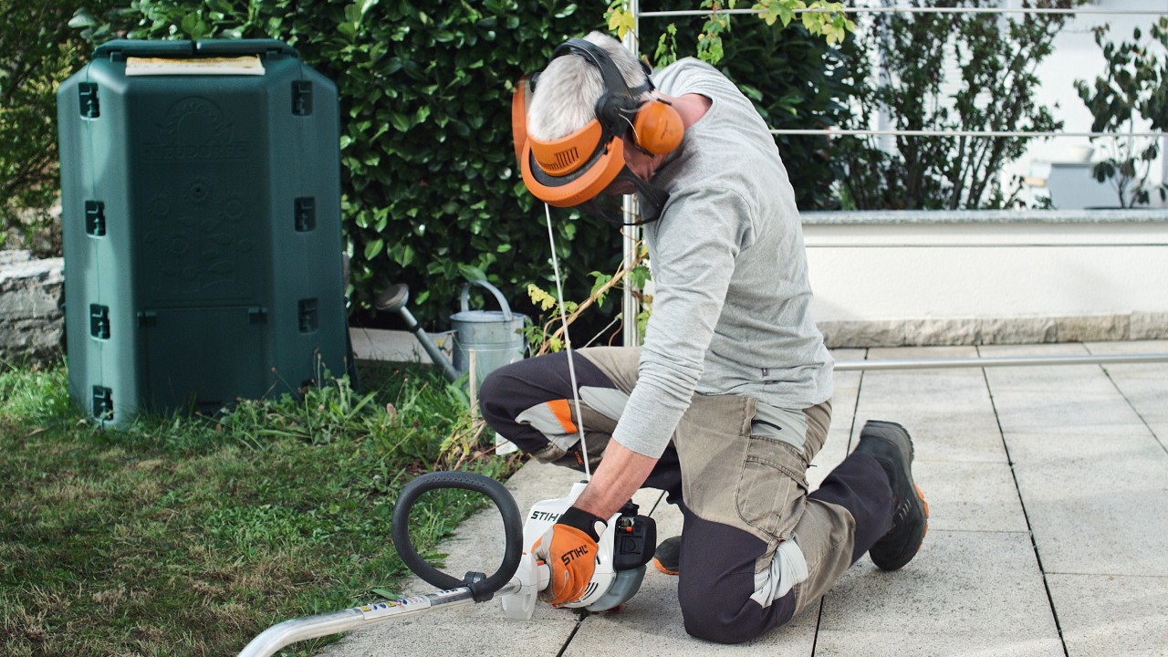 Suojavaatteita käyttävä henkilö vetämässä uudelleen bensiinikäyttöisen STIHL FS 38 -raivaussahan käynnistysnarusta