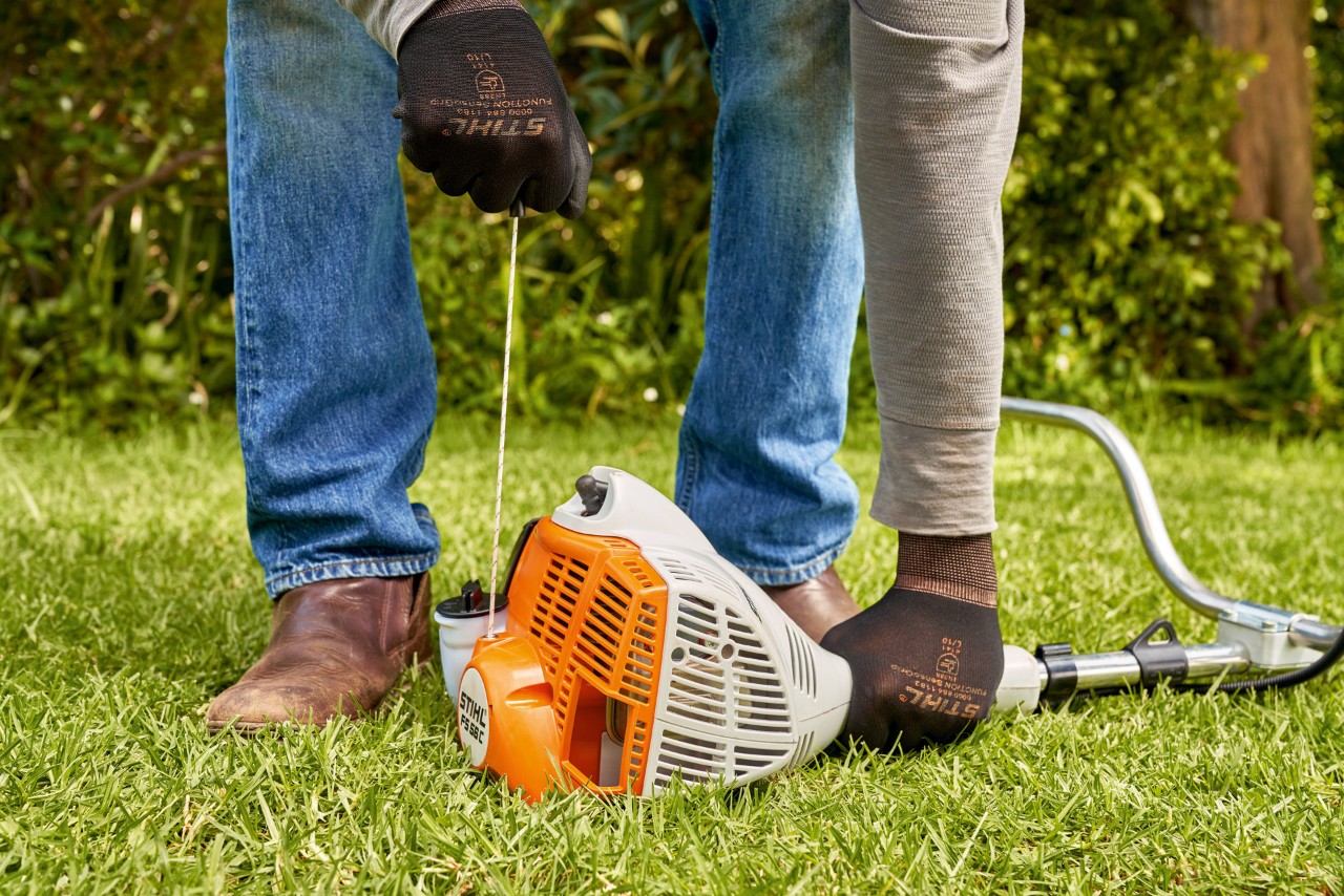Mies vetämässä bensiinikäyttöisen STIHL FS 56 -raivaussahan käynnistysnarua 