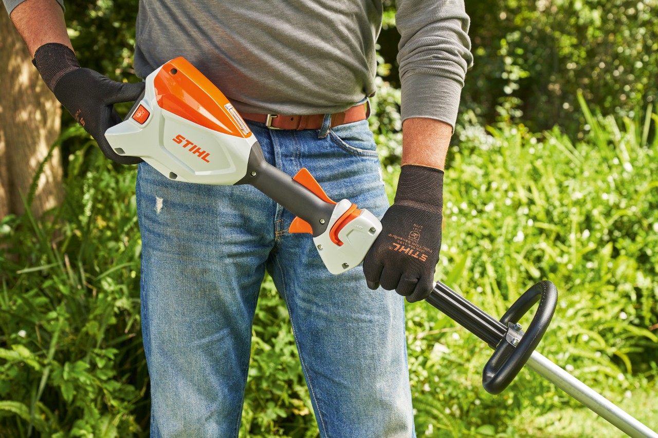Suojakäsineitä käyttävä mies tarkistamassa akkukäyttöisen STIHL FSA 60 -raivaussahan akkua ennen sen käynnistämistä