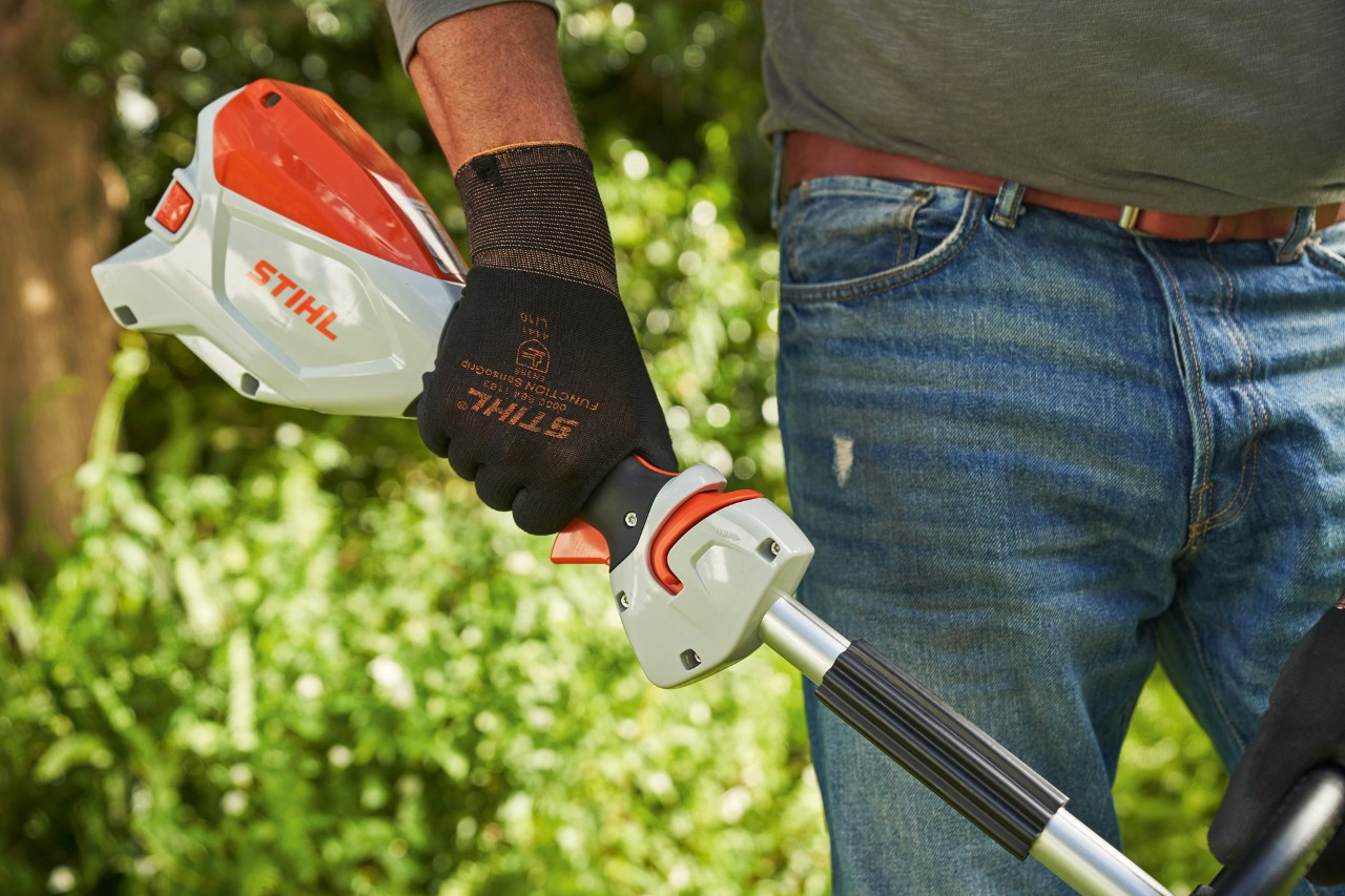 Suojakäsineitä käyttävä mies painamassa akkukäyttöisen STIHL FSA 60 -raivaussahan liipaisinta 