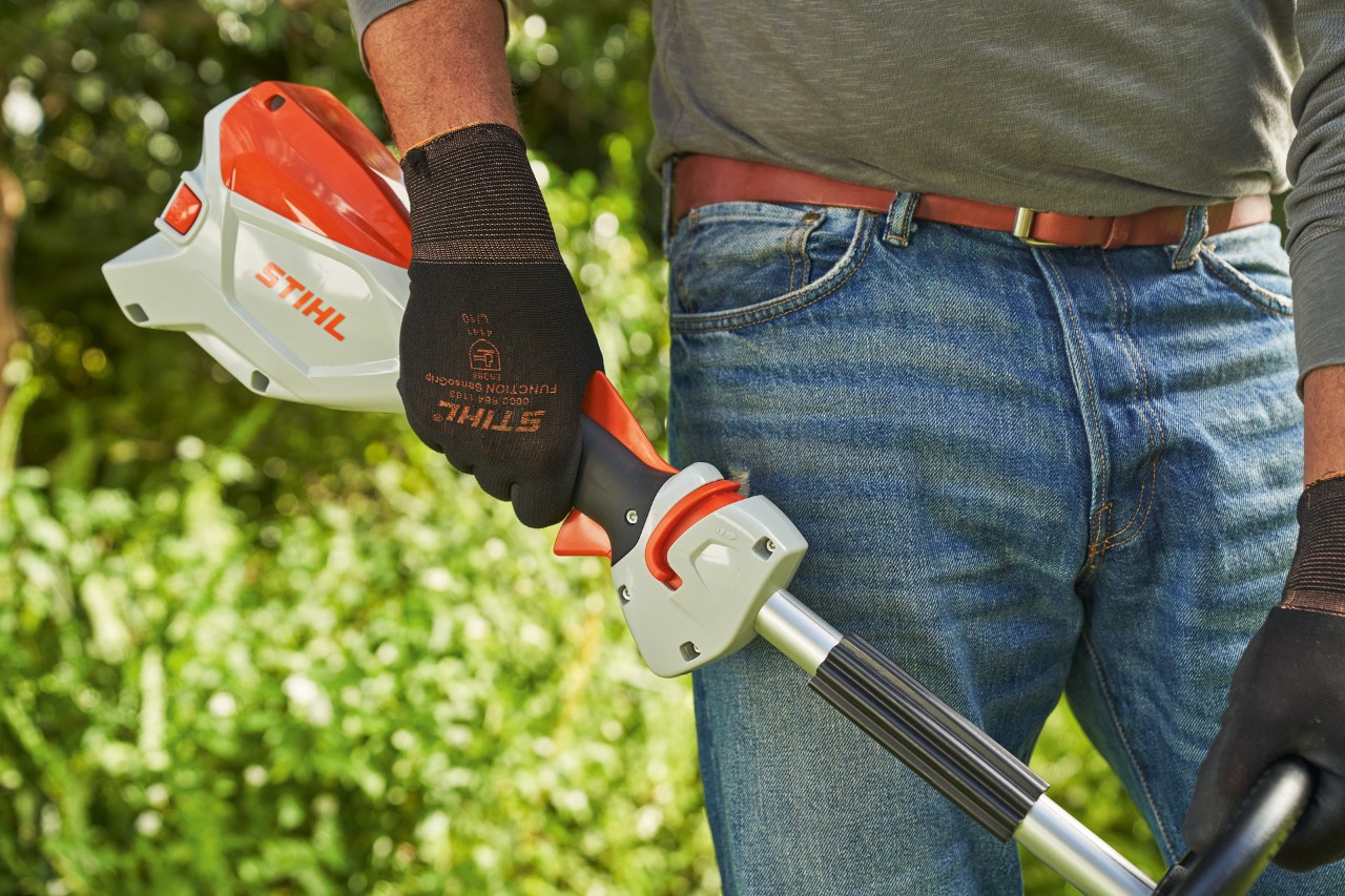 Suojakäsineitä käyttävä mies vapauttamassa akkukäyttöisen STIHL FSA 60 -raivaussahan liipaisinta sen sammuttamiseksi