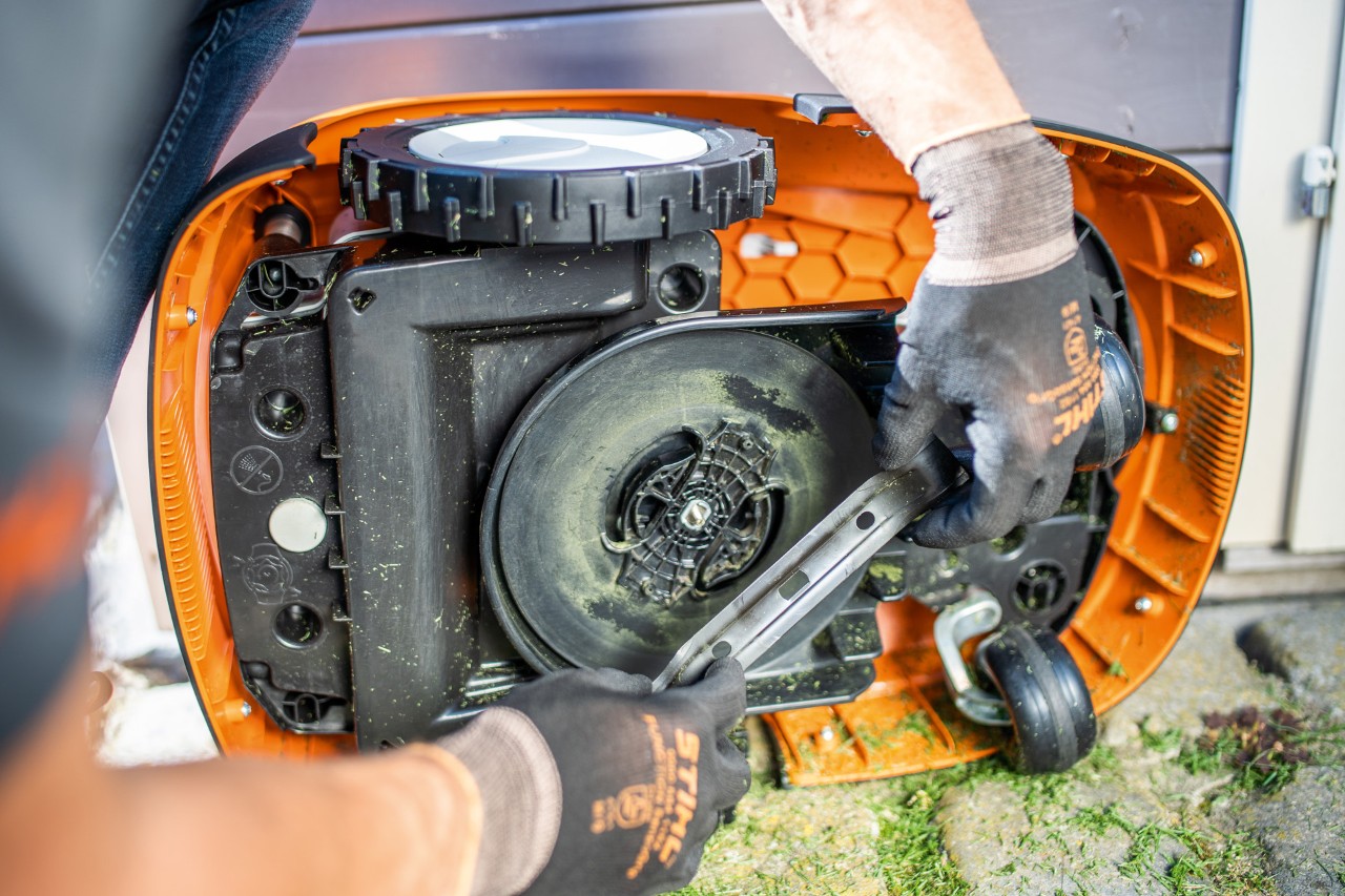 Henkilö tarkastamassa STIHL iMOW® -robottiruohonleikkurin terää