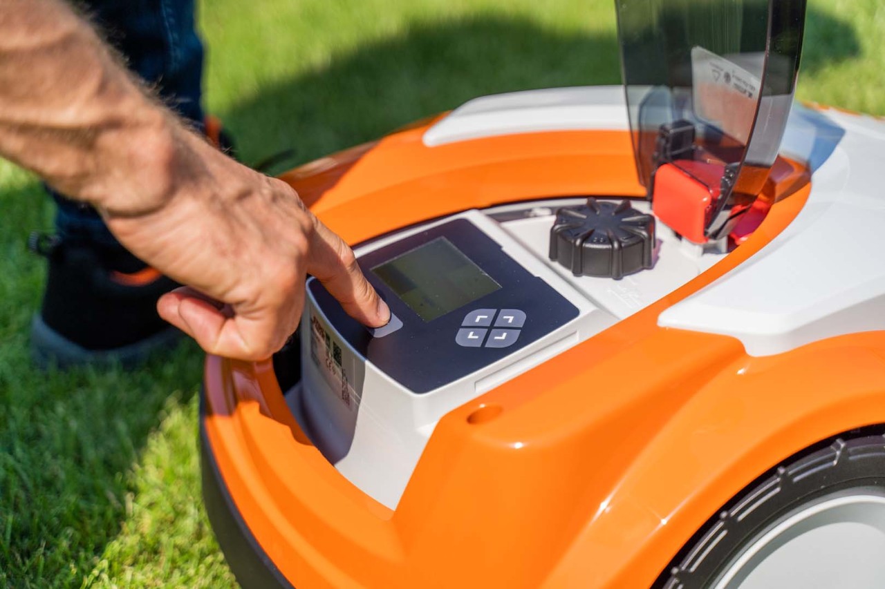 Henkilö painamassa STIHL iMOW® 422 -robottiruohonleikkurin ohjauspaneelin painiketta