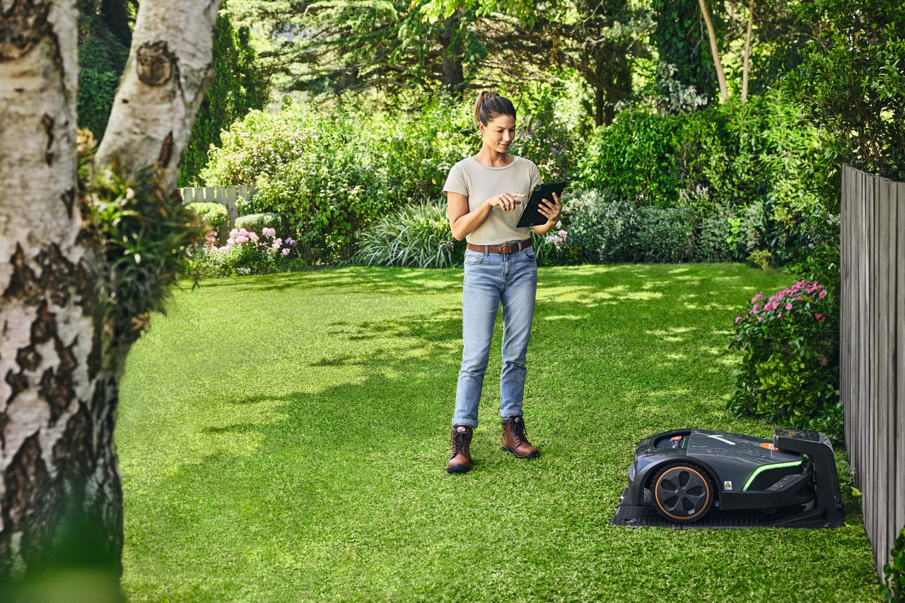 Nainen käyttämässä STIHL iMOW® EVO -leikkuria puutarhassaan tabletilla